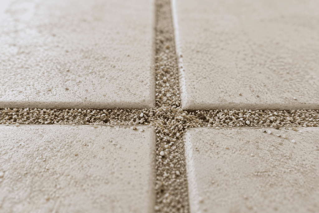Close-up of sand embedded in balcony tile grout - the result of wet-over-dry cleaning without a prior vacuum step