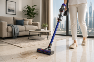 Cordless vacuum cleaner removing sand and dust from tile floor in a UAE apartment